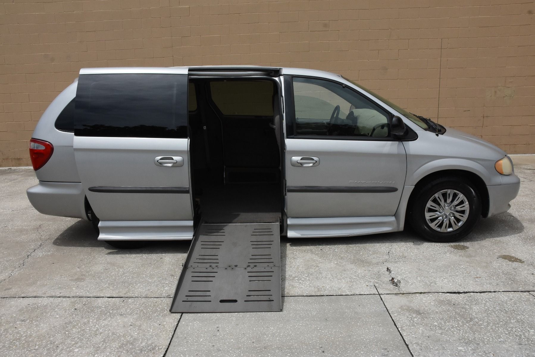 Passenger side of a silver 2003 Dodge Grand Caravan Wheelchair Van, with ramp deployed