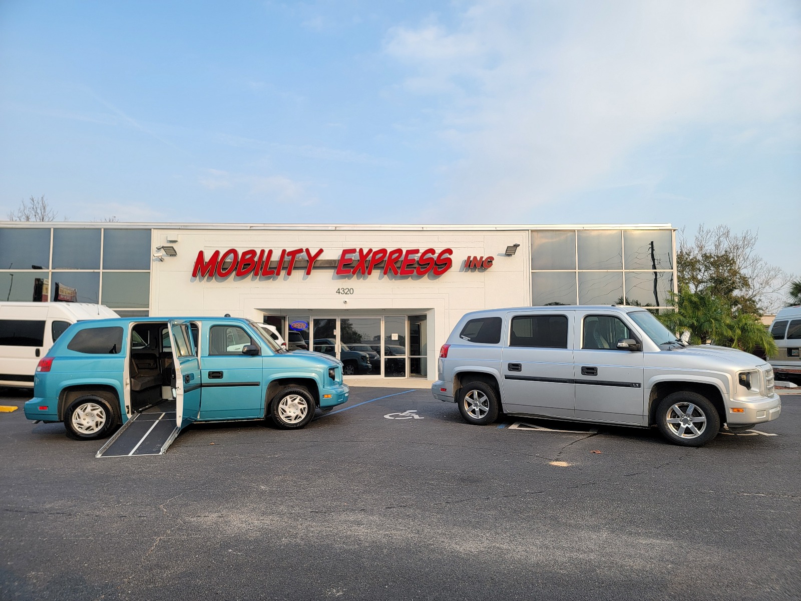 Silver Ford Explorer wheelchair accessible SUV with the ramp deployed from the open passenger side rear door.