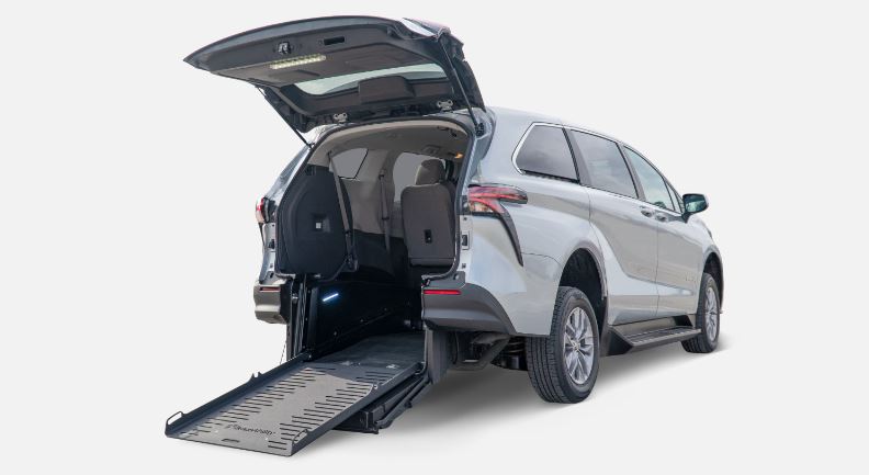 Silver Toyota Sienna with rear entry wheelchair van conversione ramp deployed from open rear hatch.