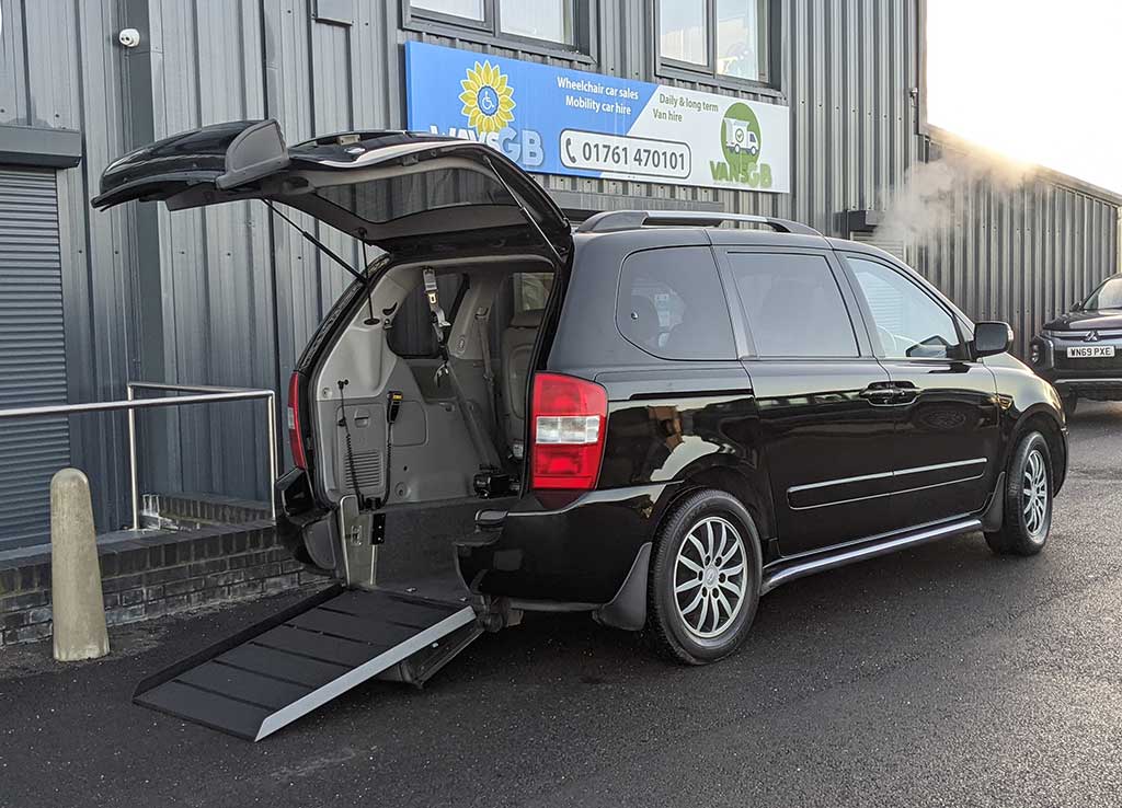 Black Kia Sedona Wheelchair Van with ramp deployed, rear view