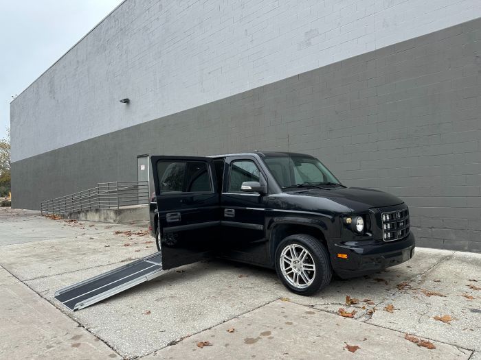 Blue Ford Explorer wheelchair accessible SUV with the ramp deployed from the open passenger side rear door.